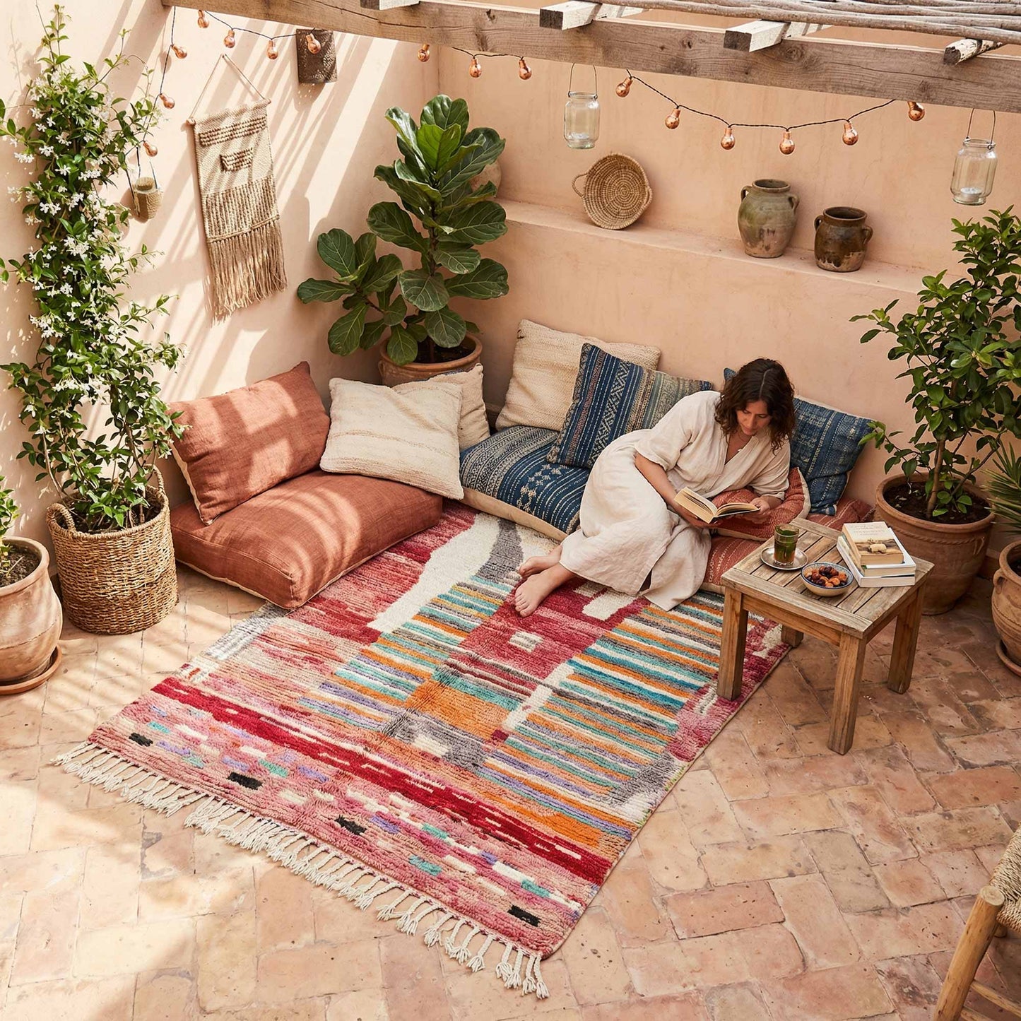Tapis berbère marocain Kadhena B25CLBO13 rose multicolore dans un coin détente lumineux.
