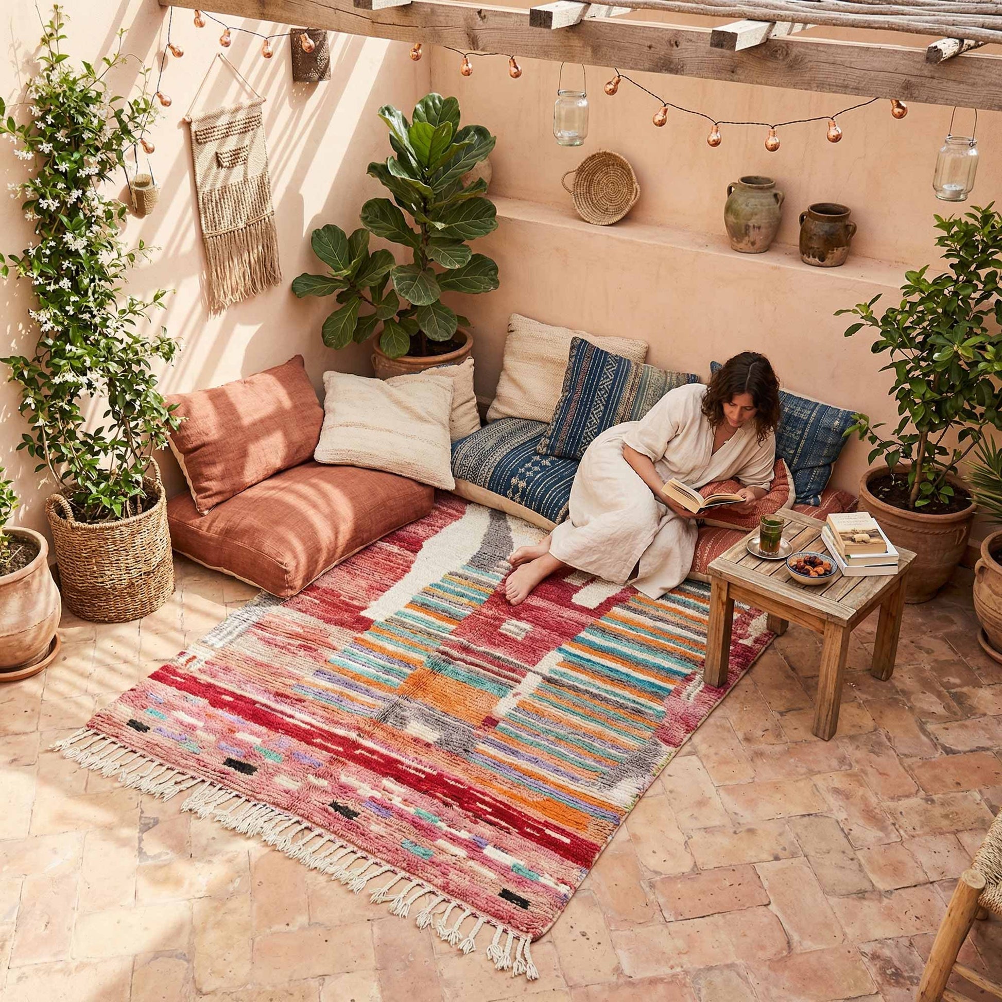 Tapis berbère marocain Kadhena B25CLBO13 rose multicolore dans un coin détente lumineux.
