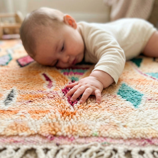 Bébé allongé sur le tapis Boujaad Kadhena Nora pour illustrer sa douceur.