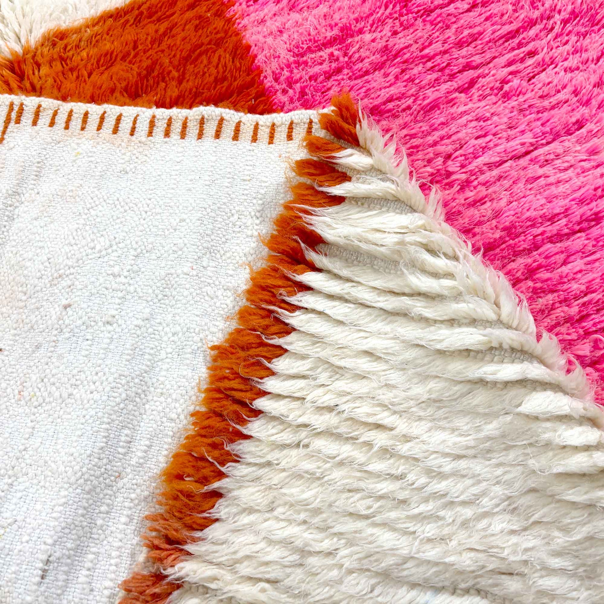 Détail des franges et des aplats colorés du tapis berbère Kadhena Paloma.