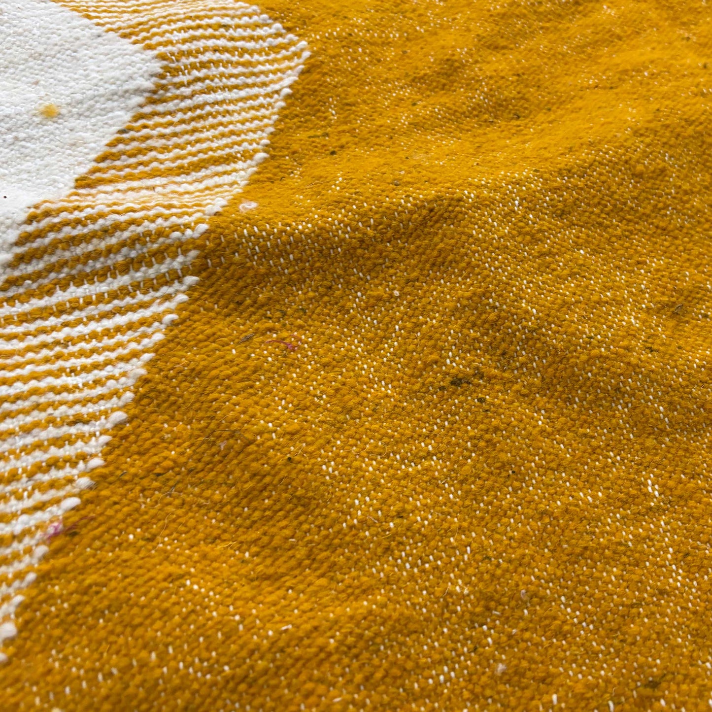 Gros plan sur le tissage du tapis Kilim Kadhena Solène en ivoire et moutarde.