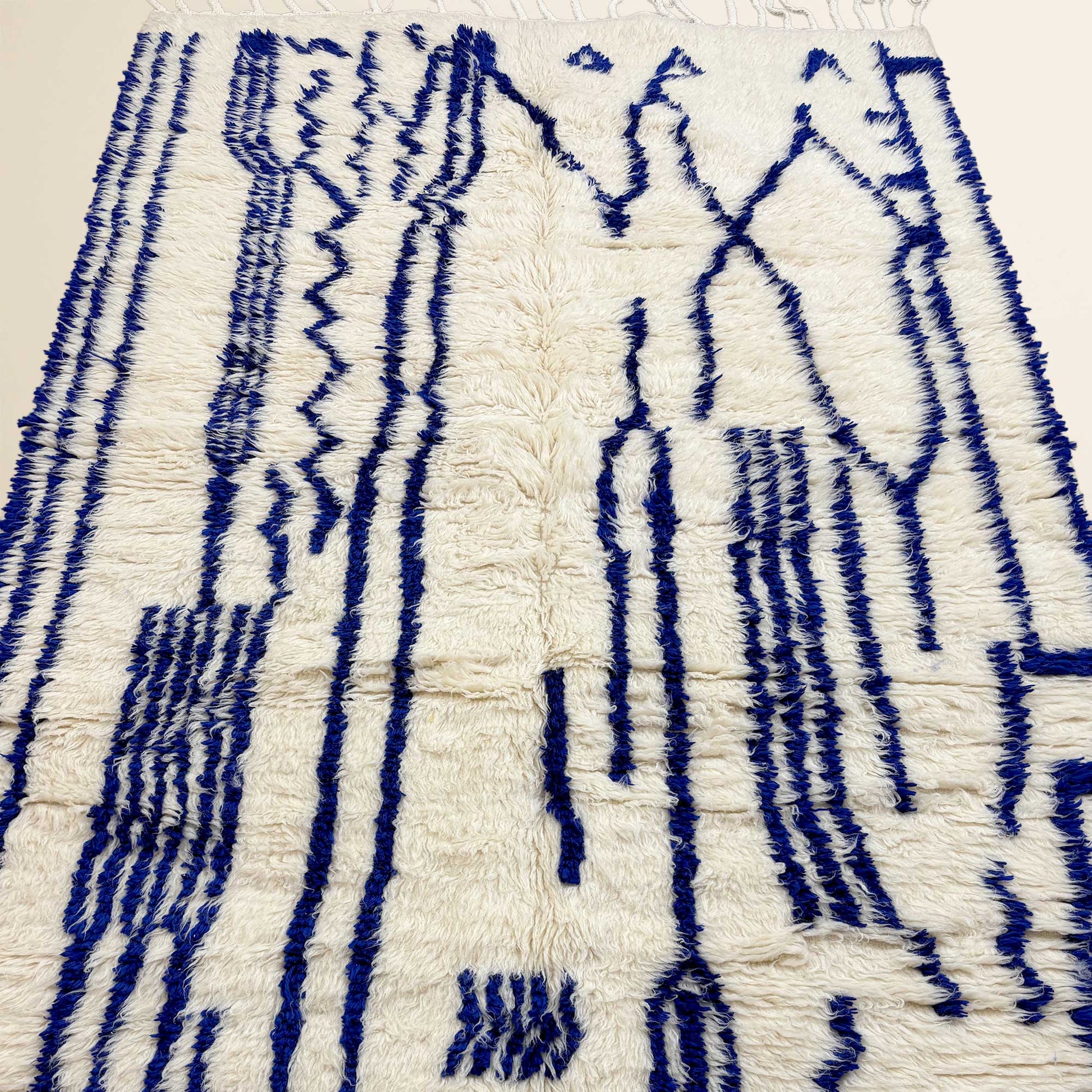 Gros plan sur la laine épaisse du tapis Azilal Kadhena Ysée en écru et bleu cobalt.