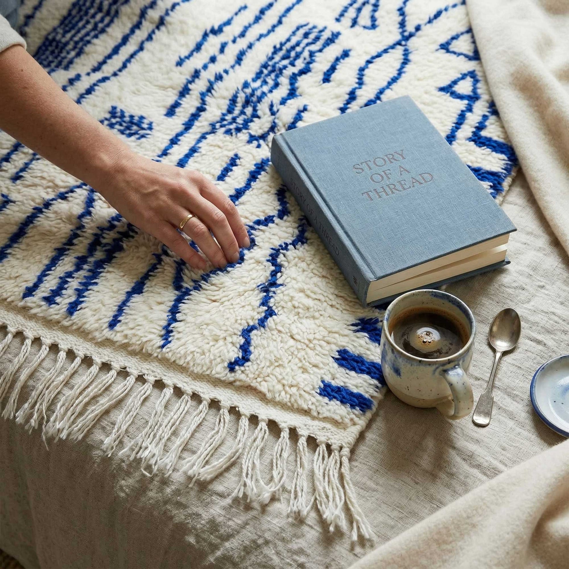 Tapis Azilal Kadhena Ysée avec livre et tasse à café pour illustrer une ambiance cosy.