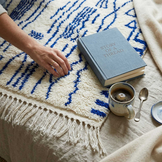 Tapis Azilal Kadhena Ysée avec livre et tasse à café pour illustrer une ambiance cosy.