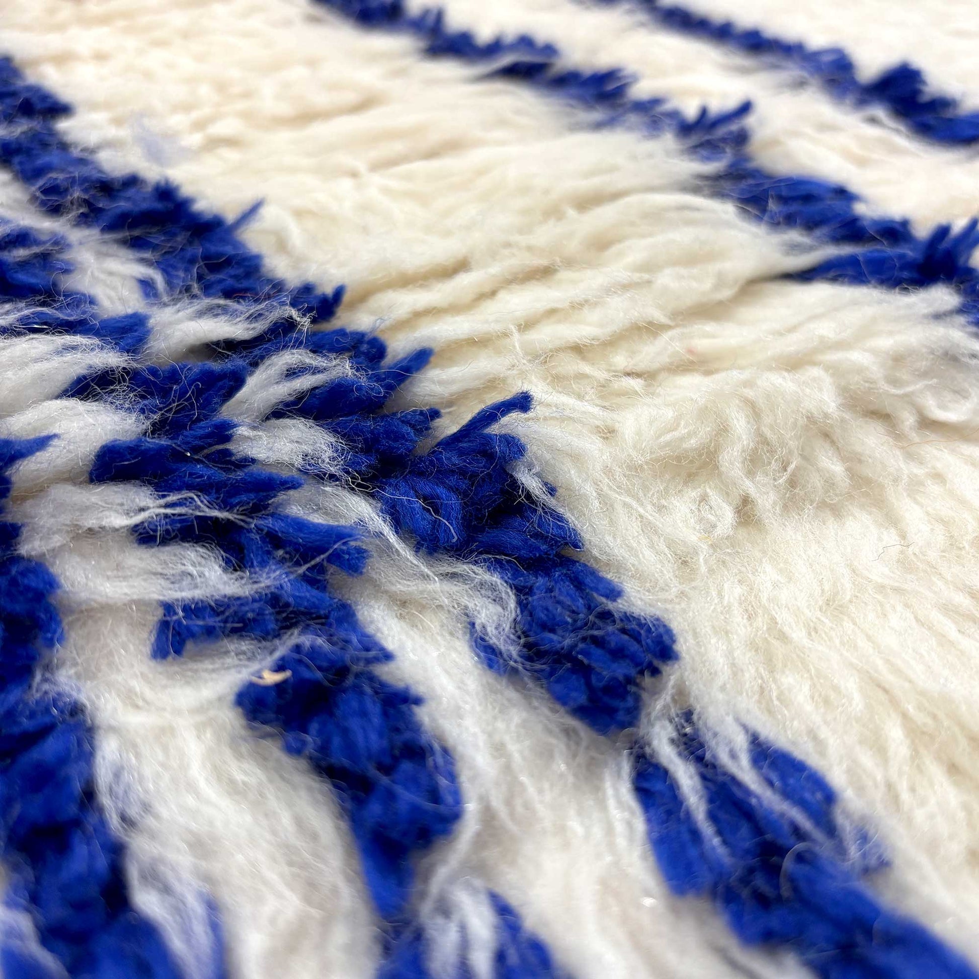 Macro sur la texture laineuse écrue et bleue du tapis Azilal Kadhena Ysée.