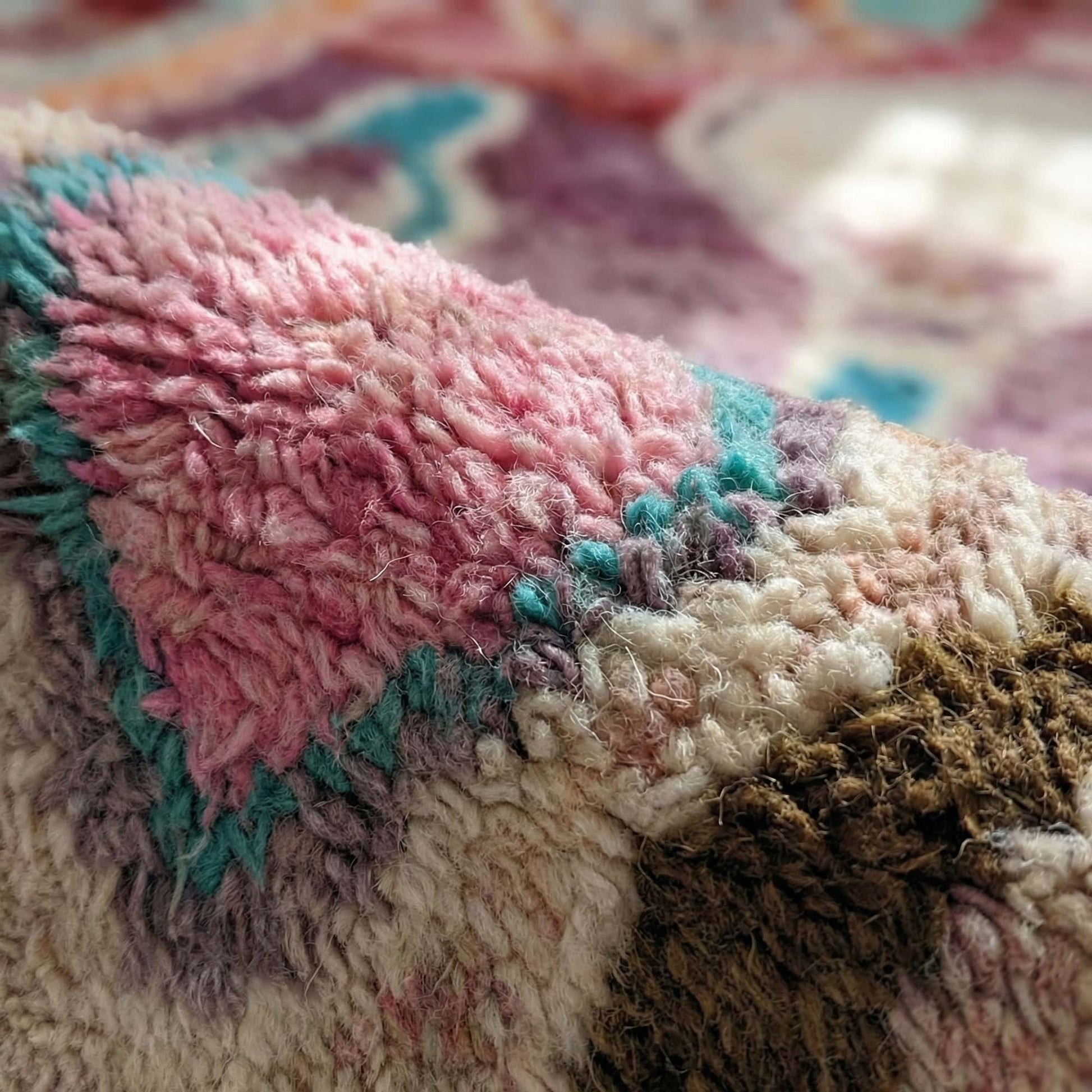 Macro sur la texture laineuse rose, lilas et turquoise du tapis berbère Kadhena Zélie.