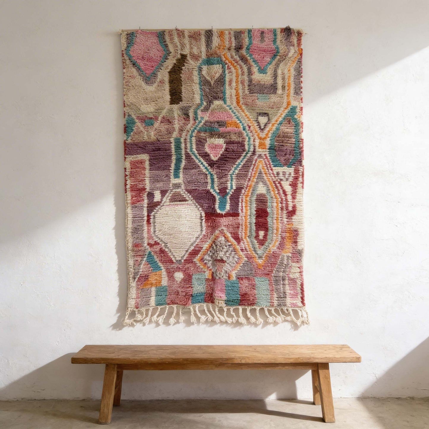 Tapis berbère Kadhena Zélie suspendu au mur avec ses motifs graphiques multicolores.