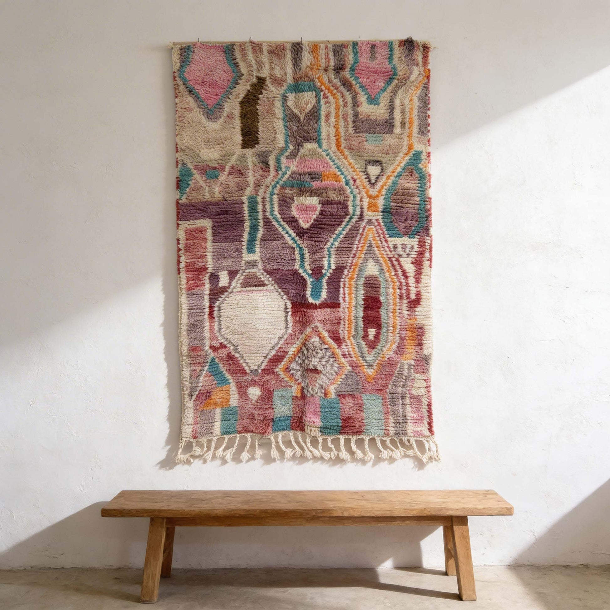 Tapis berbère Kadhena Zélie suspendu au mur avec ses motifs graphiques multicolores.